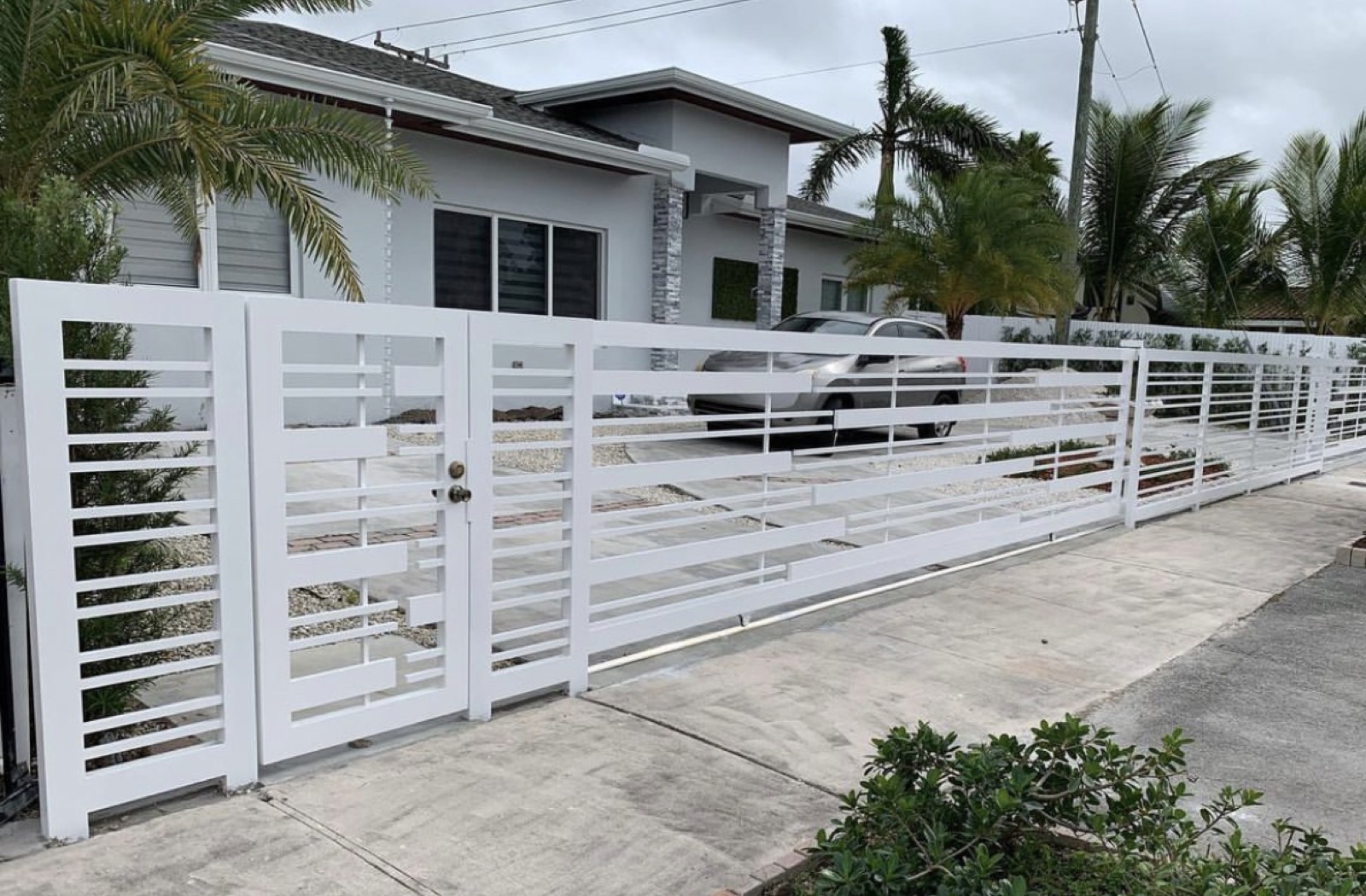 Custom white horizontal aluminum driveway gate fabricated and installed by Iron Sun Inc