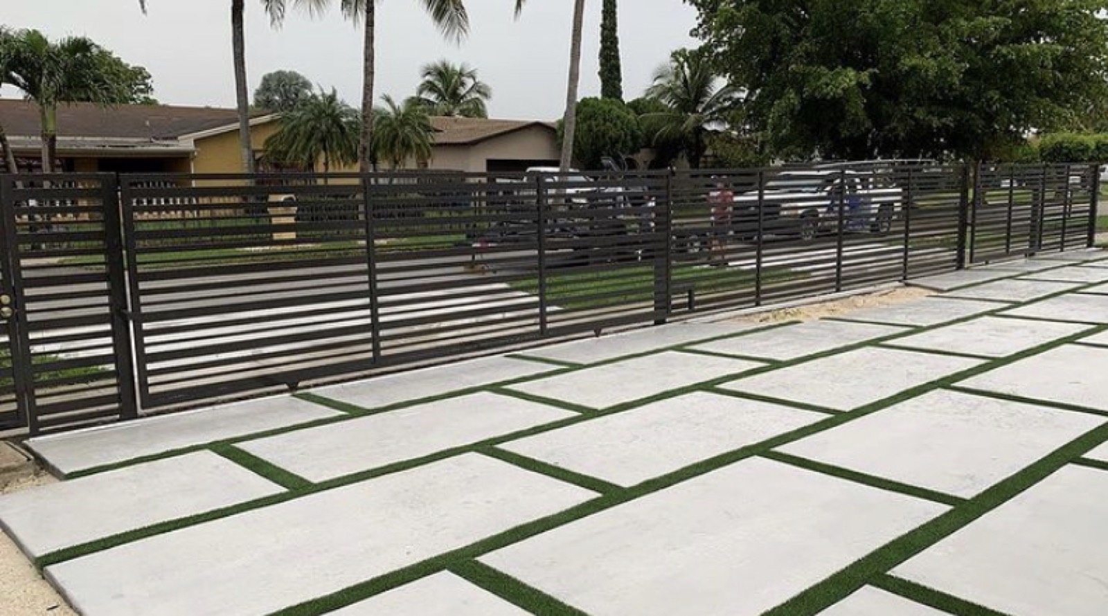 Modern black aluminum fence with concrete pavers